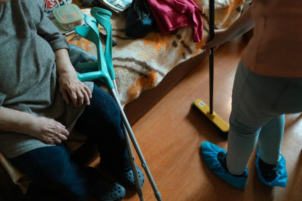 Opiekun wspiera starszą osobę trzymającą chodzik