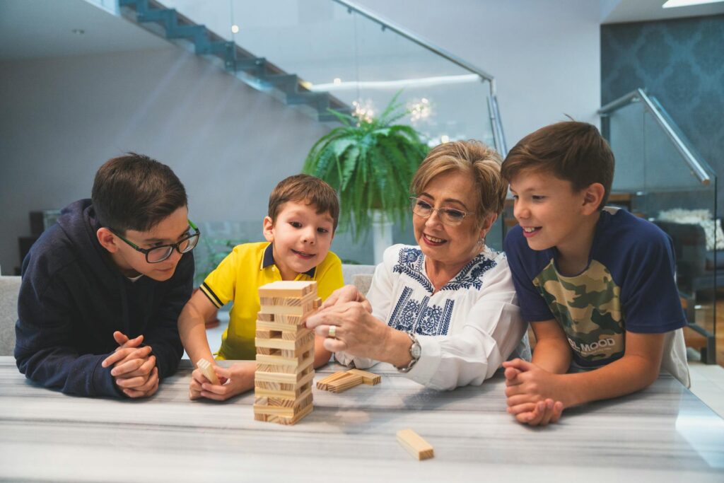 Babcia i dzieci grają w drewniane klocki Jenga